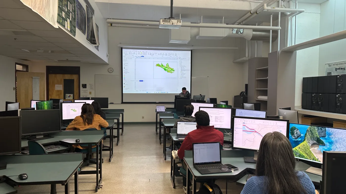Participants and computers facing a projected GIS demonstration in a classroom