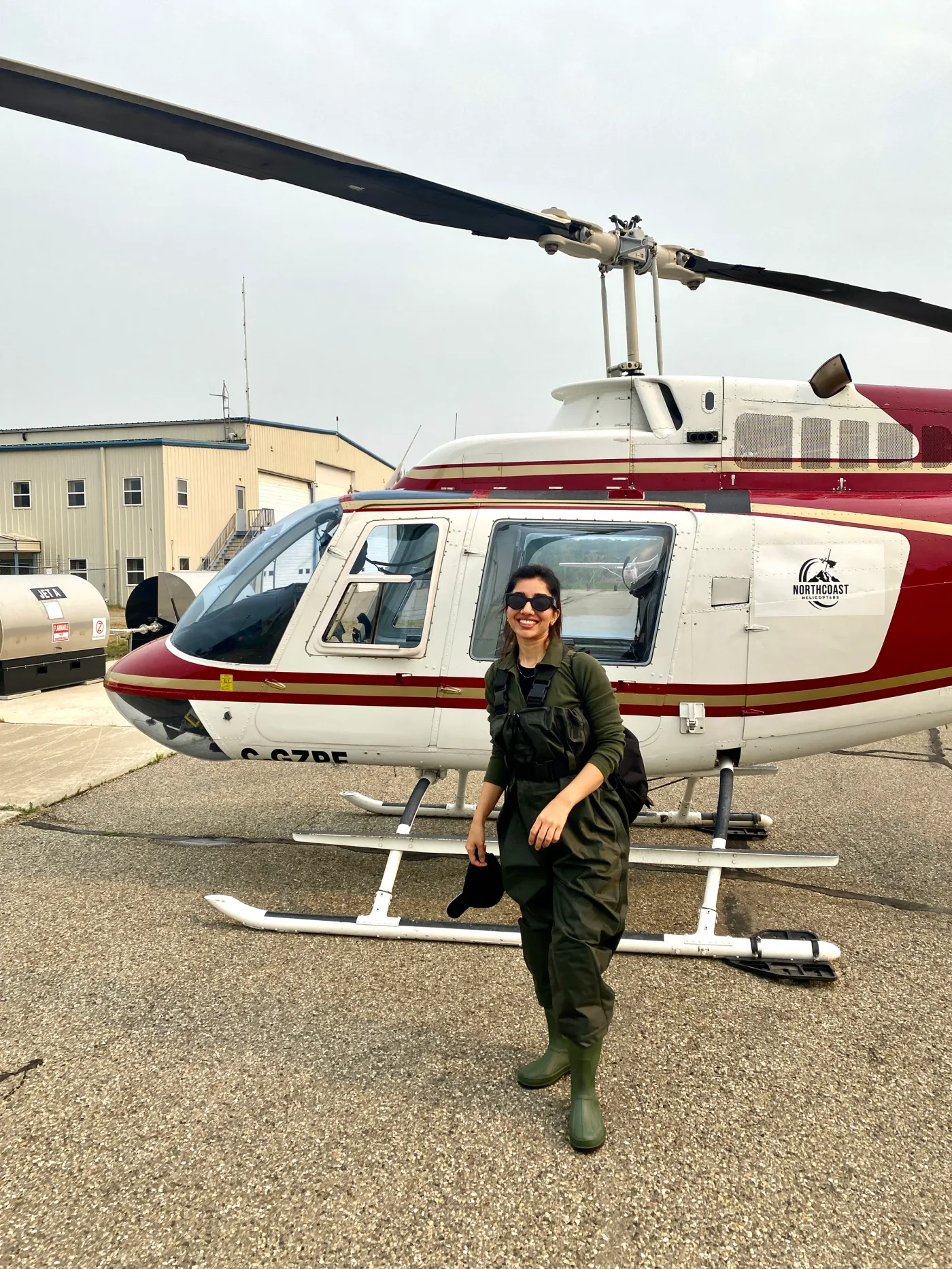 Behnoosh in field gear standing beside a red and white helicopter