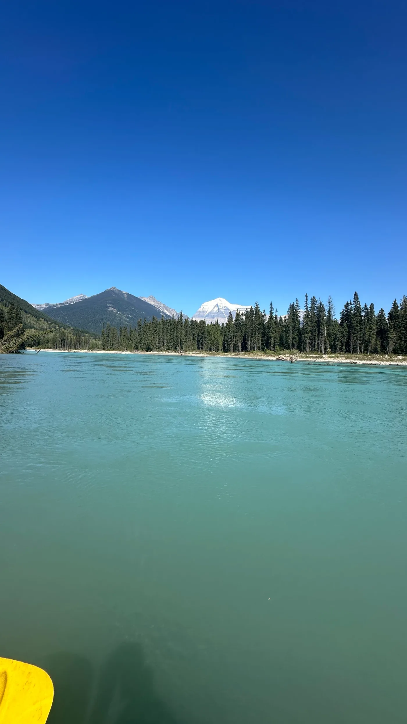 Turquoise water with forested shores and mountains beyond.